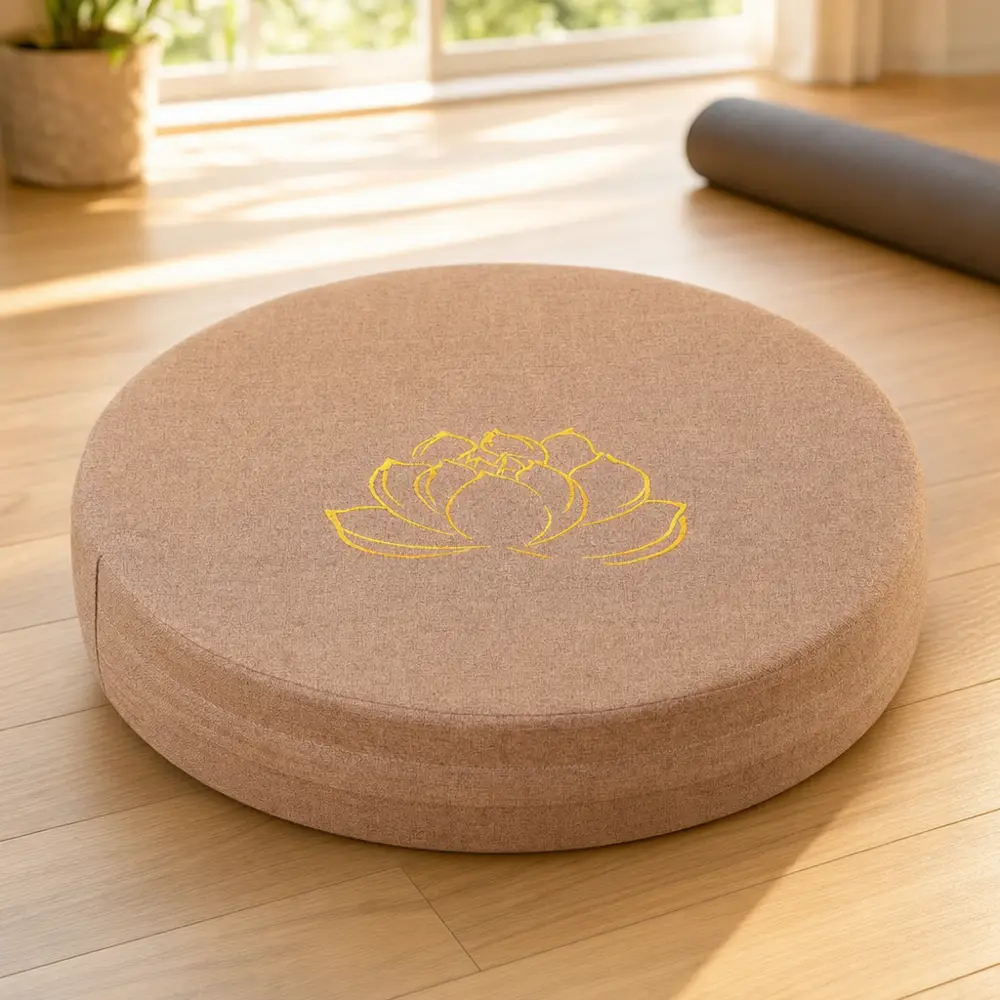 StillSeat round linen meditation cushion with gold lotus embroidery photographed beside a rolled yoga mat