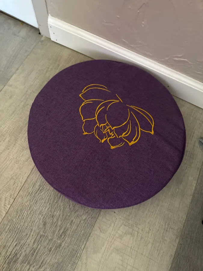 Dark purple meditation cushion with gold lotus embroidery placed on the floor, buyer photo