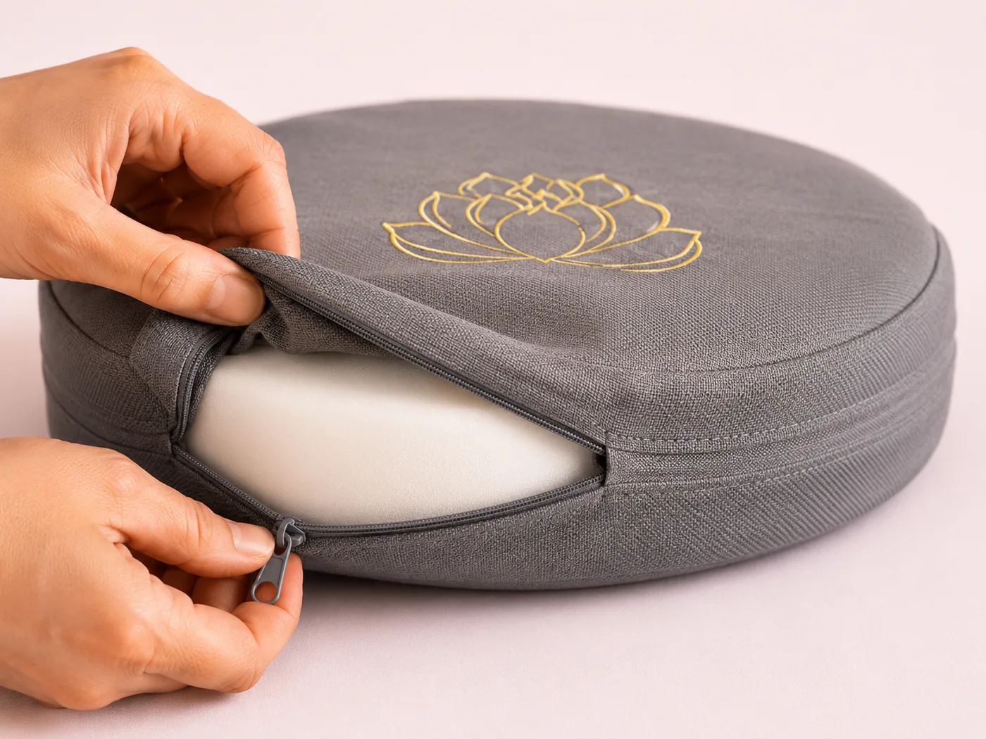 A hand unzipping the linen cover off a gray StillSeat cushion before a machine wash