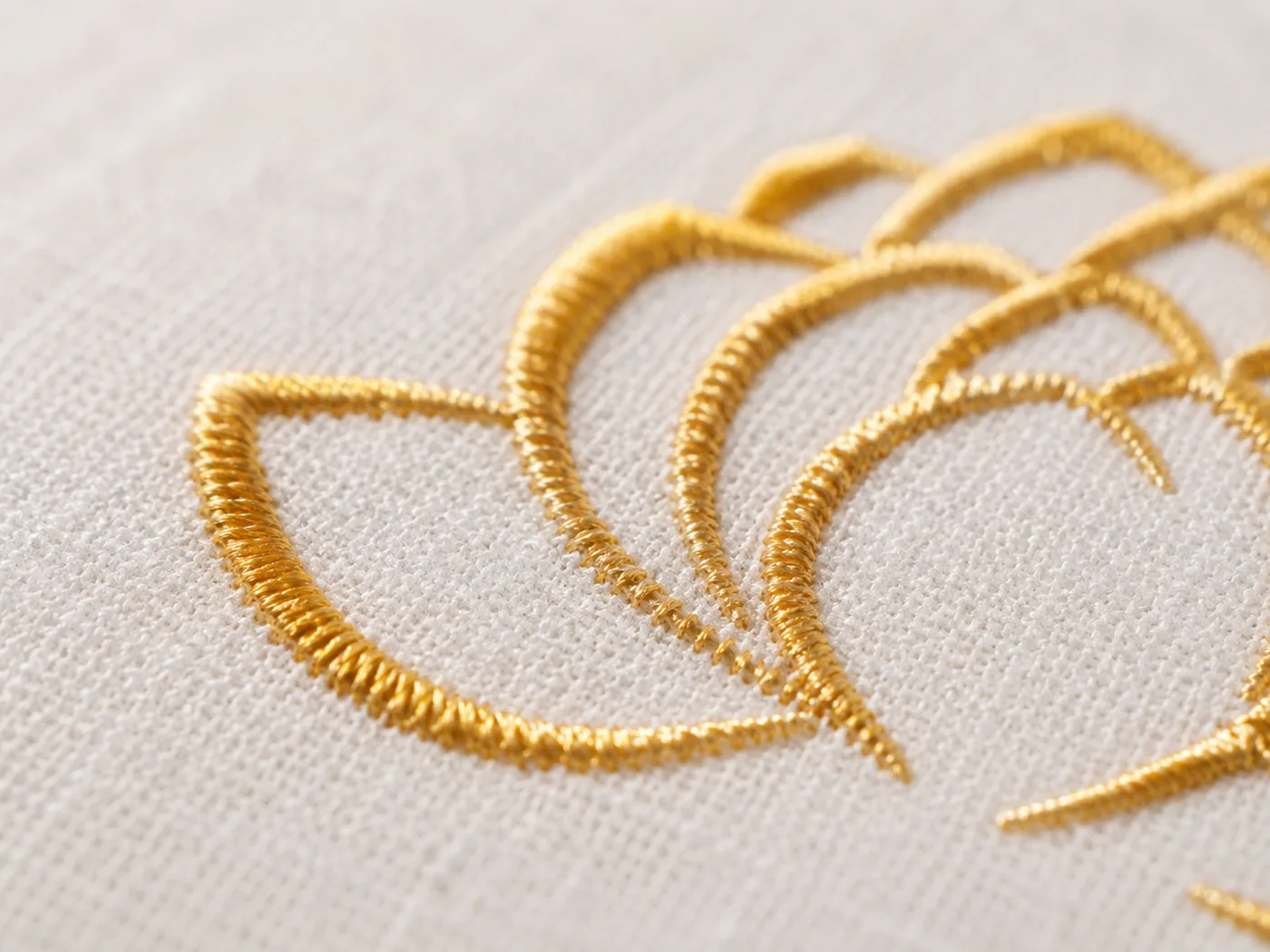 A close-up of the gold lotus embroidery stitched into the linen of a StillSeat cushion