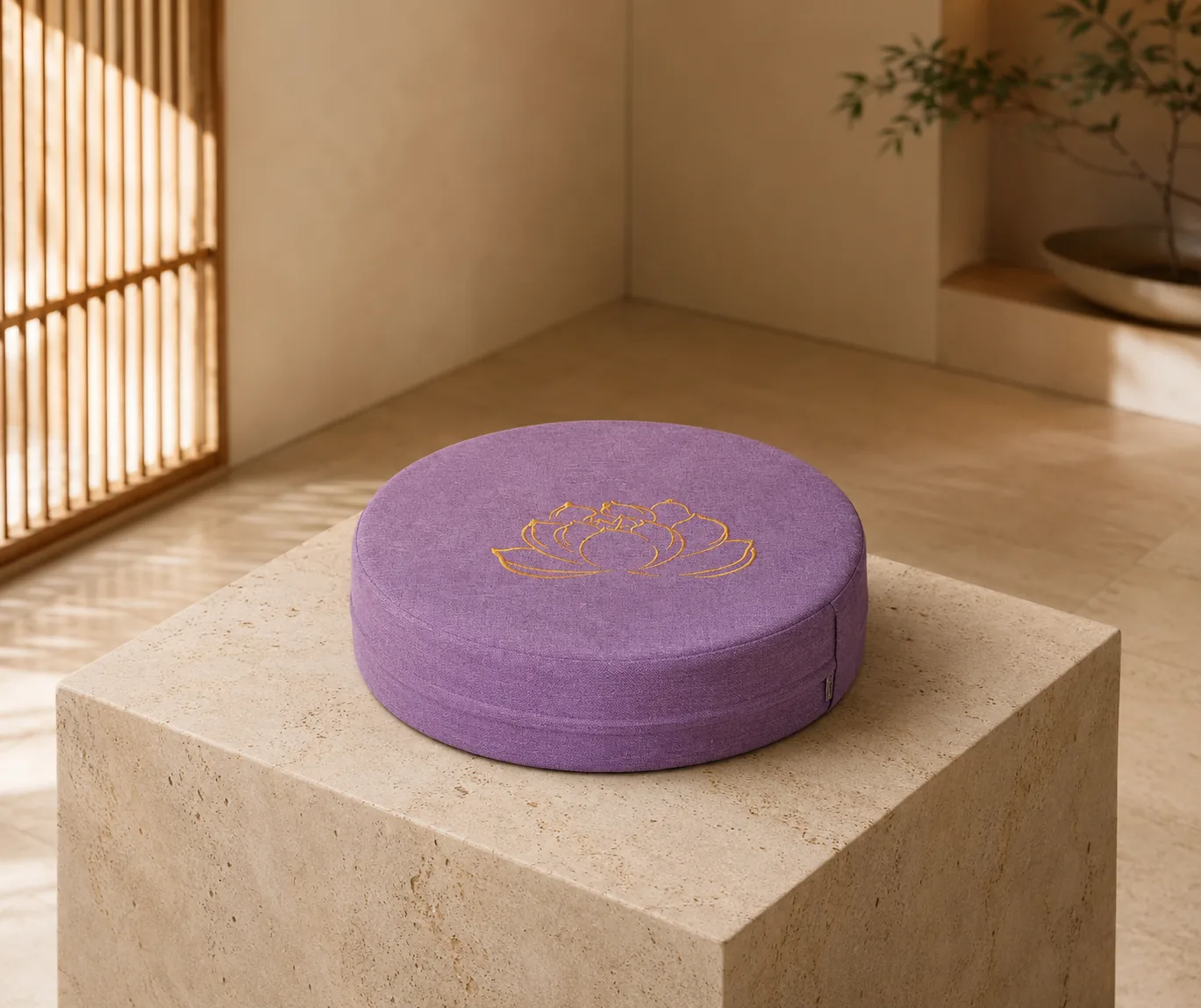 A plum StillSeat low-profile meditation cushion on a stone plinth, showing its firm round shape and gold lotus embroidery